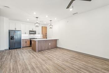 A kitchen and living room with wood flooring and a stainless steel refrigerator